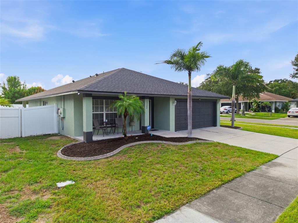 A single-story house with a green exterior, a dark roof, and a two-car garage — 15544 FLORIDA BREEZE LOOP, WIMAUMA, FL