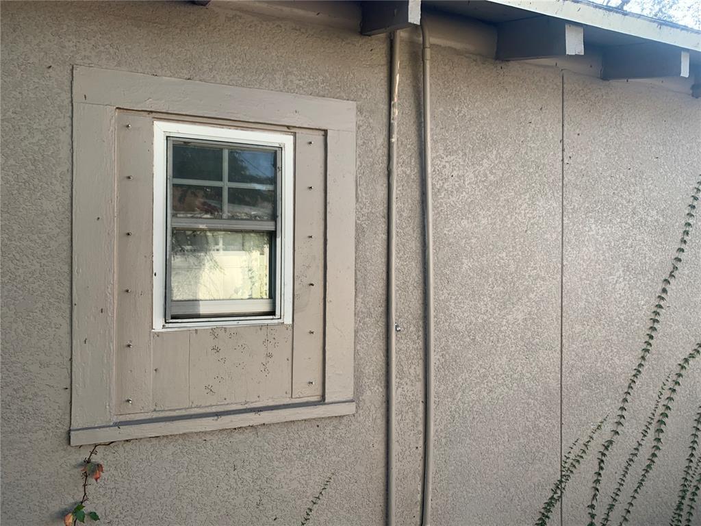 An exterior view of a stucco wall featuring a window with a wood-trimmed frame — 1880 SYLVAN DRIVE, CLEARWATER, FL