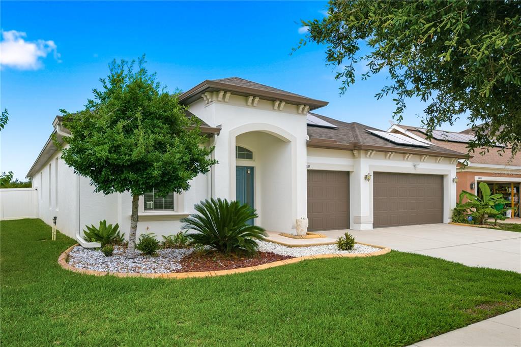 A single-story house with a white stucco exterior, two garage doors, and a landscaped yard — 6410 FALLING OAK TRAIL, WESLEY CHAPEL, FL