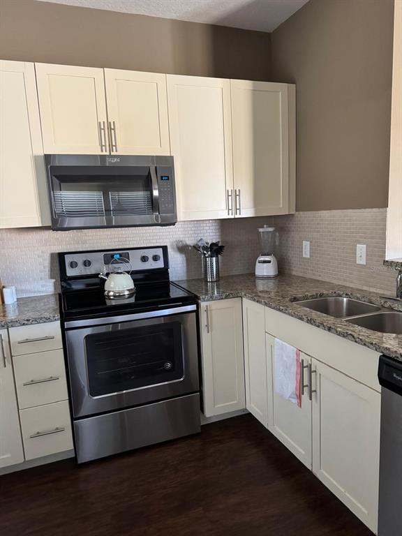 A kitchen features cream-colored cabinets, stainless steel appliances, granite countertops, and a tiled backsplash — 8981 SHINE DRIVE, KISSIMMEE, FL