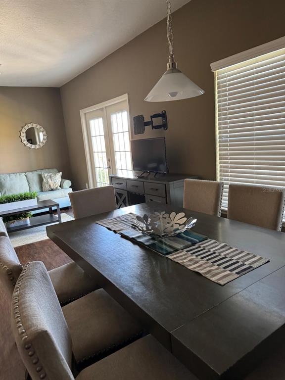 A dining room features a dark wood table, upholstered chairs, and a view of a living area — 8981 SHINE DRIVE, KISSIMMEE, FL