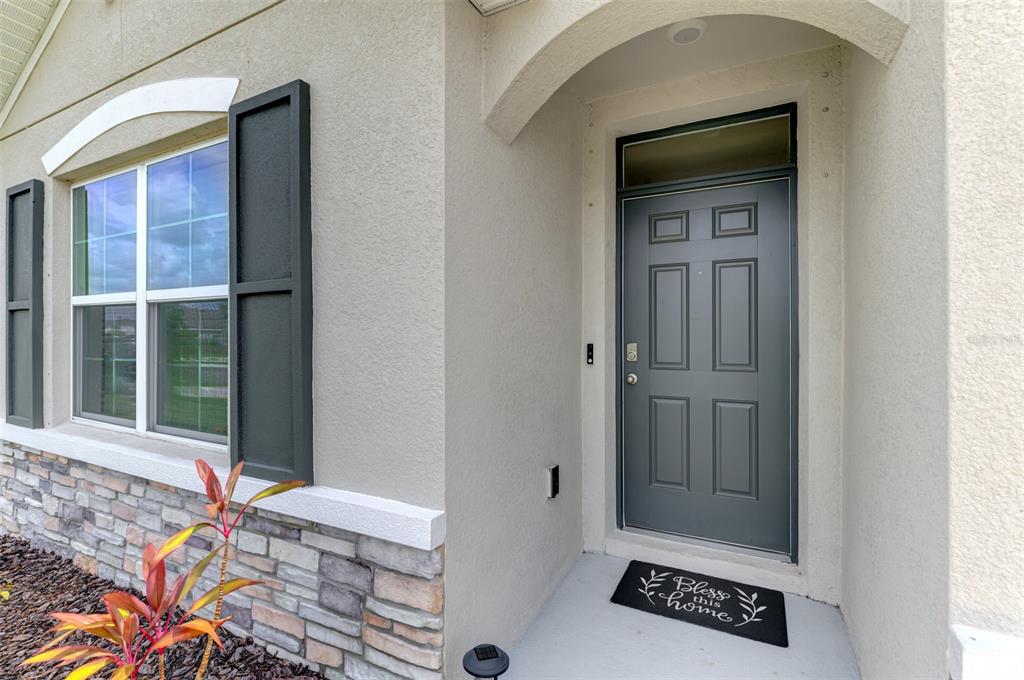 The exterior view shows a gray front door with a transom window and stone siding — 17733 CANOPY PLACE, BRADENTON, FL