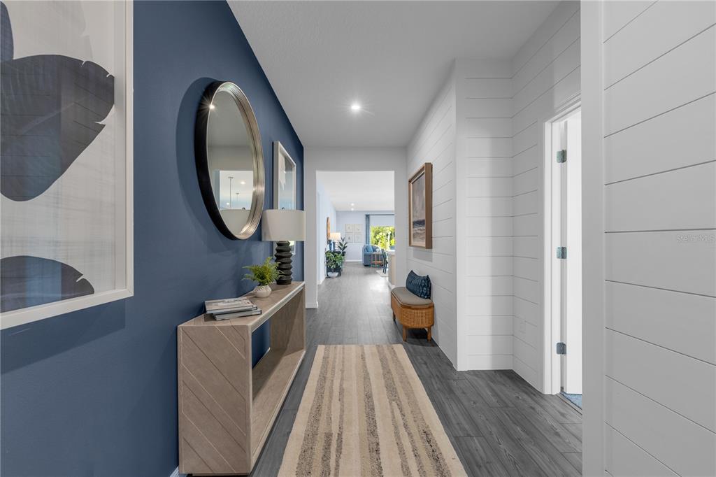 A hallway features a blue accent wall, white shiplap, a console table, and wood flooring — 5824 CLIFFBOW LOOP, LEESBURG, FL