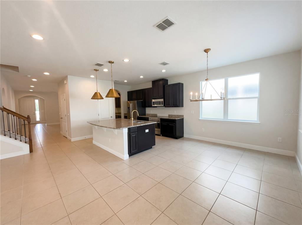 A kitchen features dark cabinets, granite countertops, a central island, and stainless steel appliances — 4309 SALTMARSH SPARROW DRIVE, WINDERMERE, FL