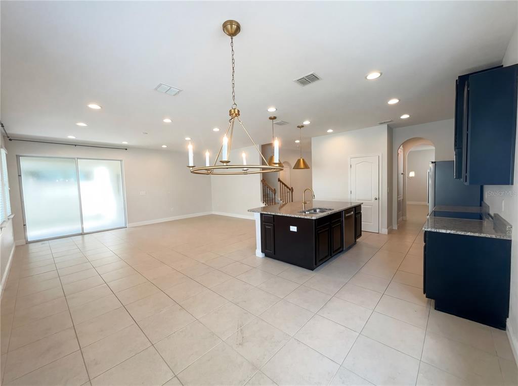 A bright, empty living room features light tile flooring, recessed lighting, and sliding glass doors — 4309 SALTMARSH SPARROW DRIVE, WINDERMERE, FL