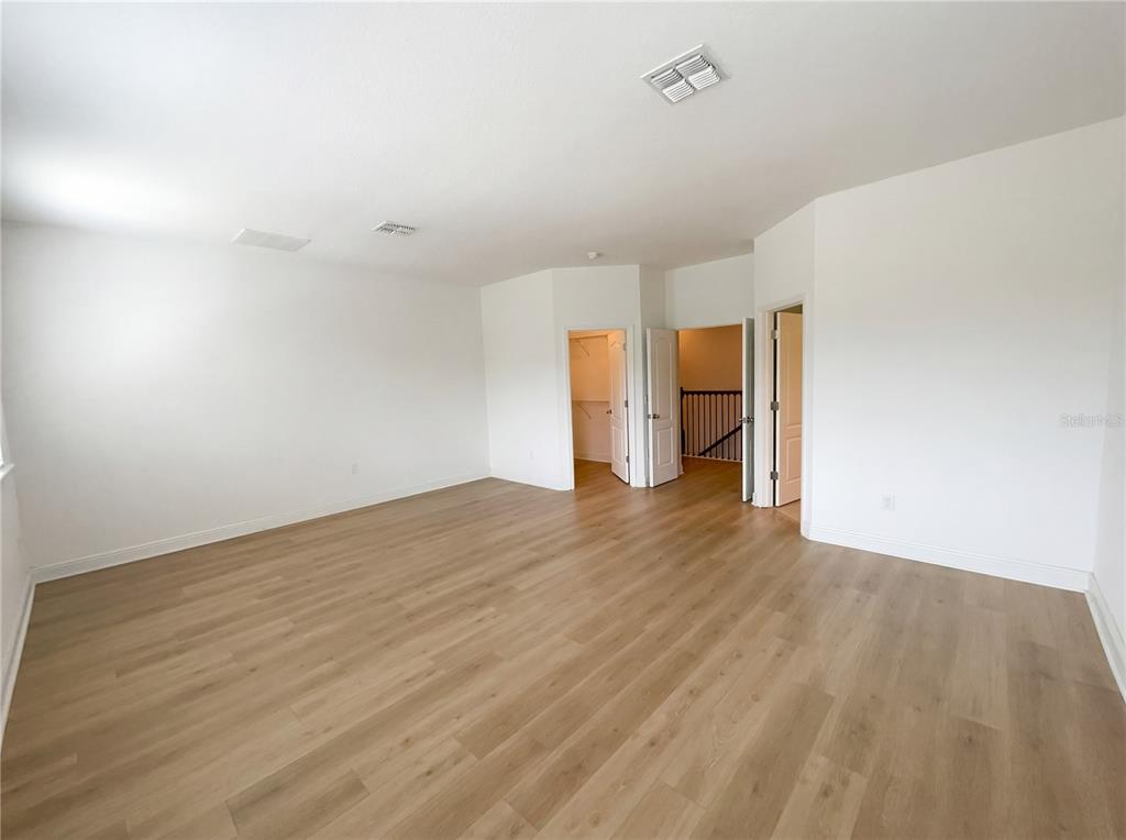An empty room with light wood-look flooring, white walls, and two open doorways — 4309 SALTMARSH SPARROW DRIVE, WINDERMERE, FL