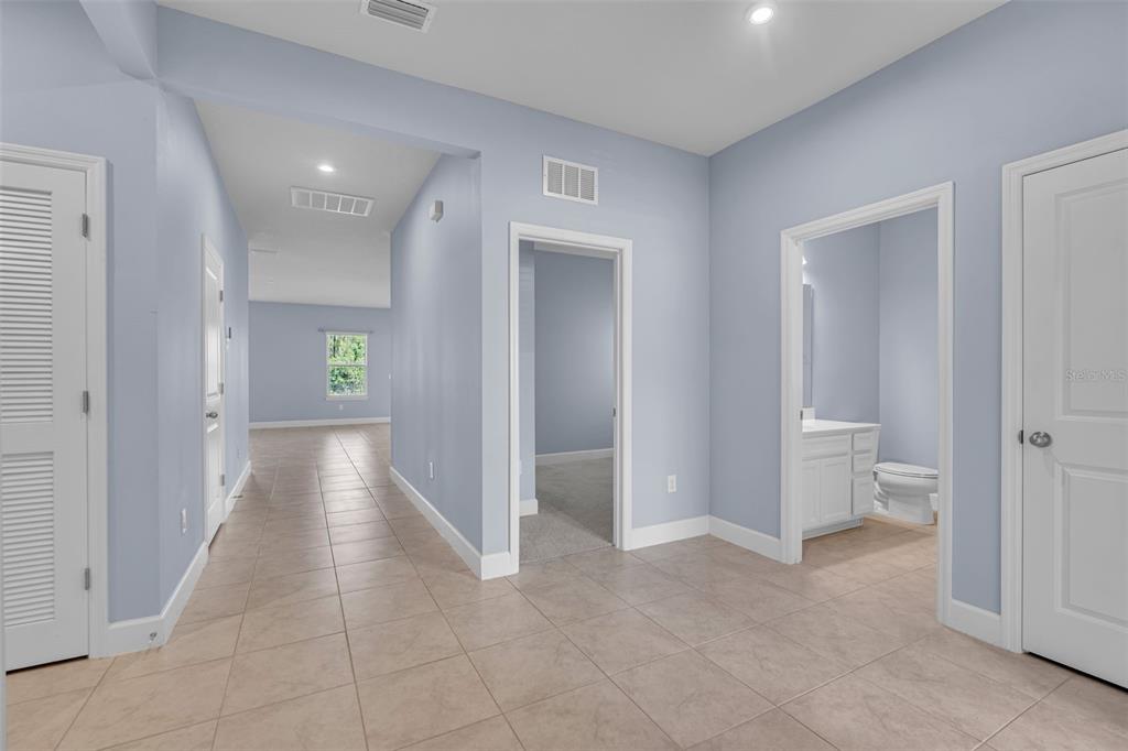 A hallway with light blue walls and tile flooring leads to a bathroom and bedroom — 9810 EVENTIDE TRAIL, PARRISH, FL