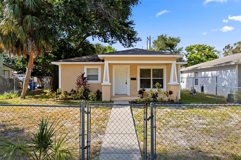A single-story tan house with a front porch and a chain-link fence — 980 13TH AVENUE S, ST PETERSBURG, FL