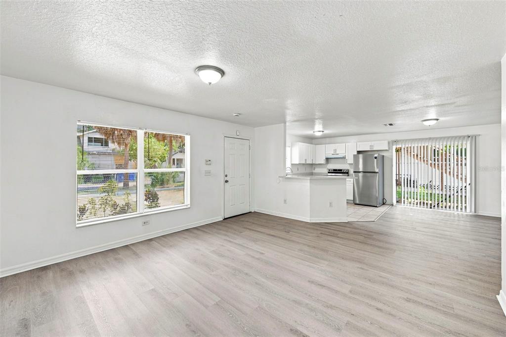 An open-concept living room and kitchen with light wood-look flooring and white walls — 980 13TH AVENUE S, ST PETERSBURG, FL