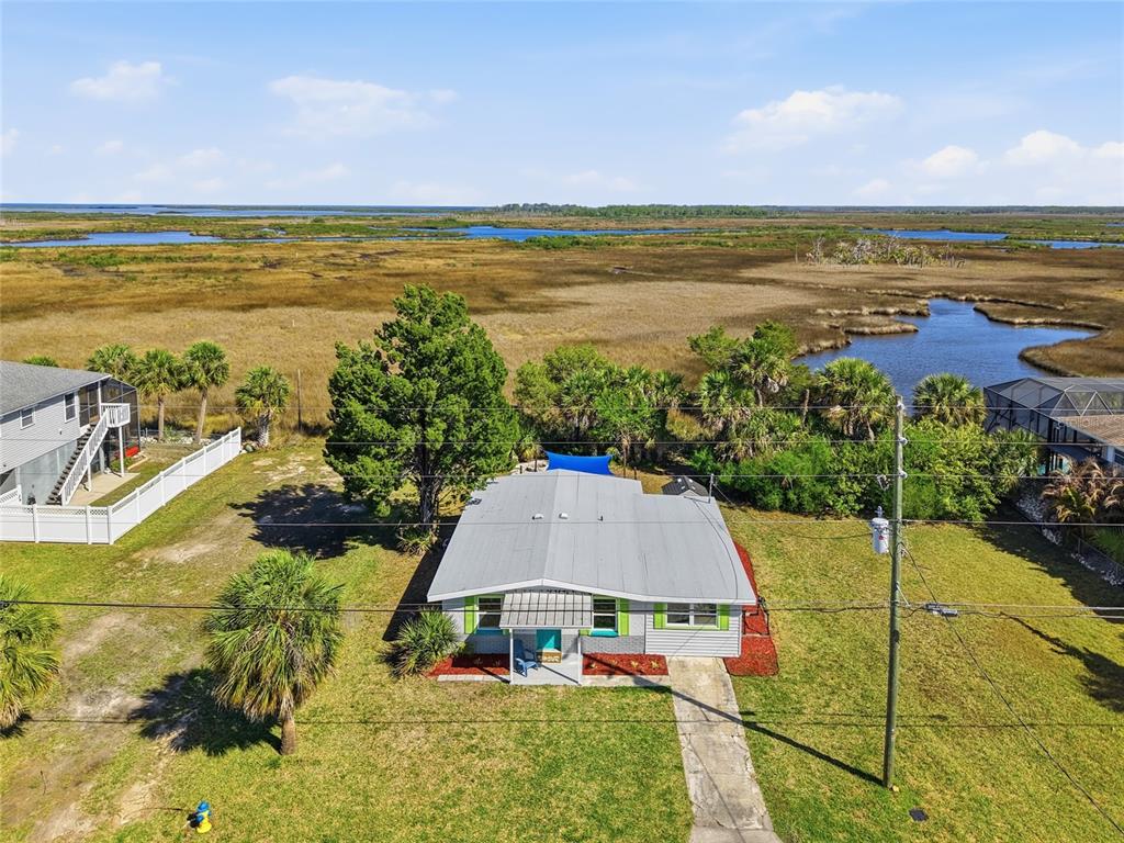 A bright turquoise door is flanked by lime green shutters and a metal jellyfish wall decoration — 4021 EAGLE NEST DRIVE, HERNANDO BEACH, FL