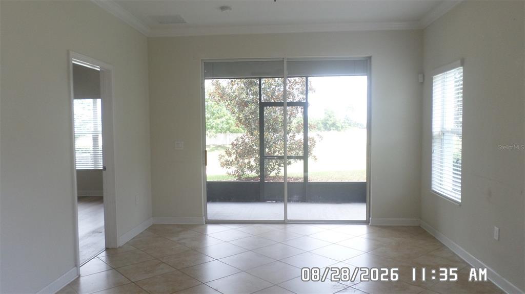 A room with tile flooring, a sliding glass door to a screened patio, and windows — 3547 FAIRWATERS COURT UNIT F, CLERMONT, FL