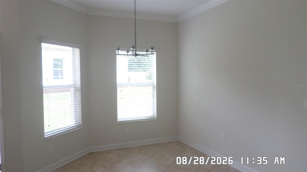 An empty dining area with tile flooring, a chandelier, and two windows with blinds — 3547 FAIRWATERS COURT UNIT F, CLERMONT, FL