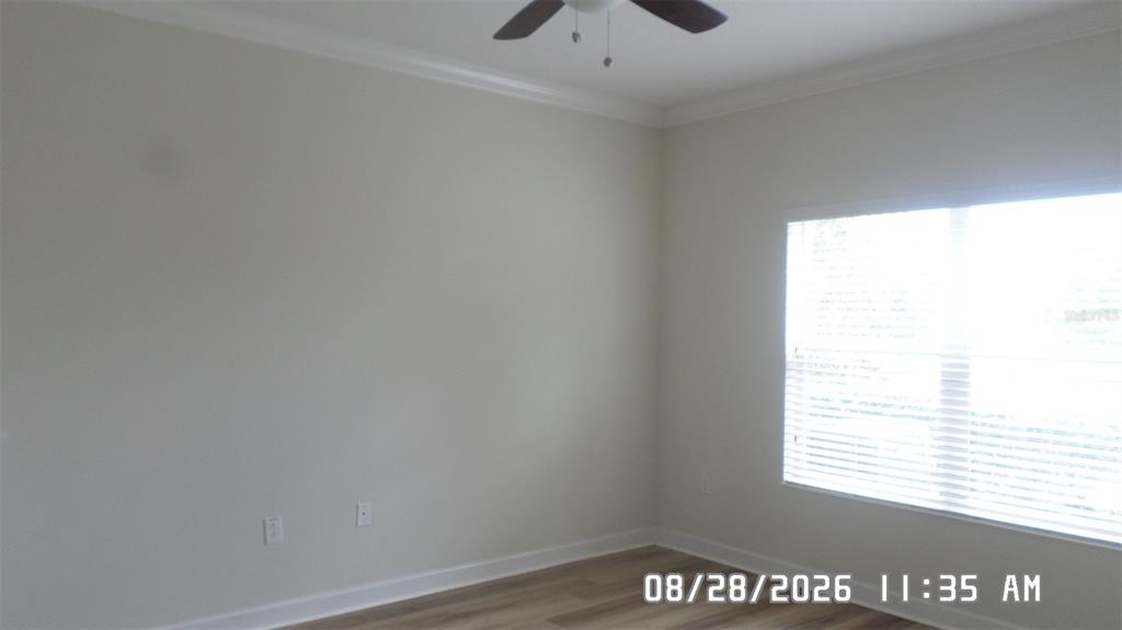 An empty bedroom features light-colored walls, wood-look flooring, a ceiling fan, and a large window — 3547 FAIRWATERS COURT UNIT F, CLERMONT, FL