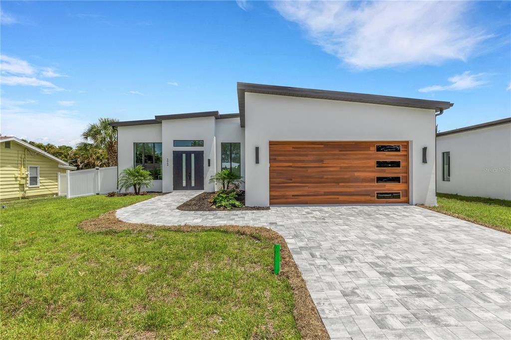 A modern single-story house features a white stucco exterior, a wood-paneled garage door, and pavers — 2069 HIBISCUS STREET, SARASOTA, FL