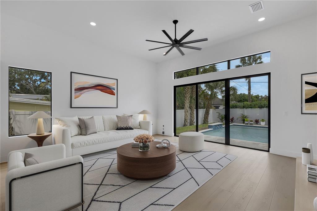 A modern living room features white walls, a large sofa, a round coffee table, and pool views — 2069 HIBISCUS STREET, SARASOTA, FL