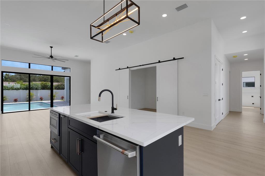 A modern kitchen island with a dark base and white countertop faces a sliding barn door — 2069 HIBISCUS STREET, SARASOTA, FL