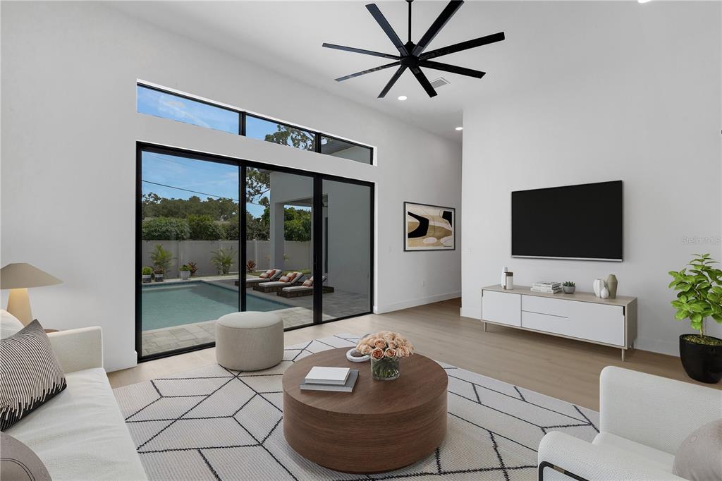 A modern living room features a large ceiling fan, sliding glass doors, and a swimming pool — 2069 HIBISCUS STREET, SARASOTA, FL
