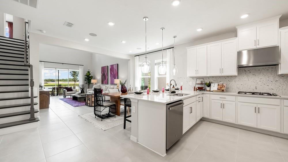 A modern open-concept kitchen features white cabinetry, a large island, and an adjacent dining area — 11400 STRONG STEM ROW, SAN ANTONIO, FL