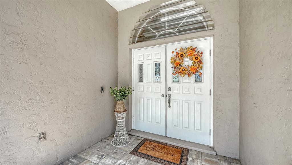 A white double front door with a decorative wreath sits under a semi-circular transom window — 4494 DIAMOND CIRCLE E, SARASOTA, FL