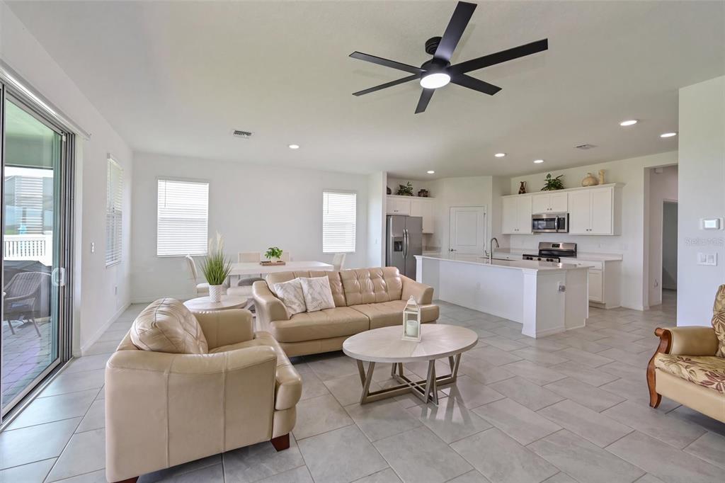 An open-concept living room and kitchen featuring light tile floors and a ceiling fan — 3519 NIGHT STAR TERRACE, PARRISH, FL