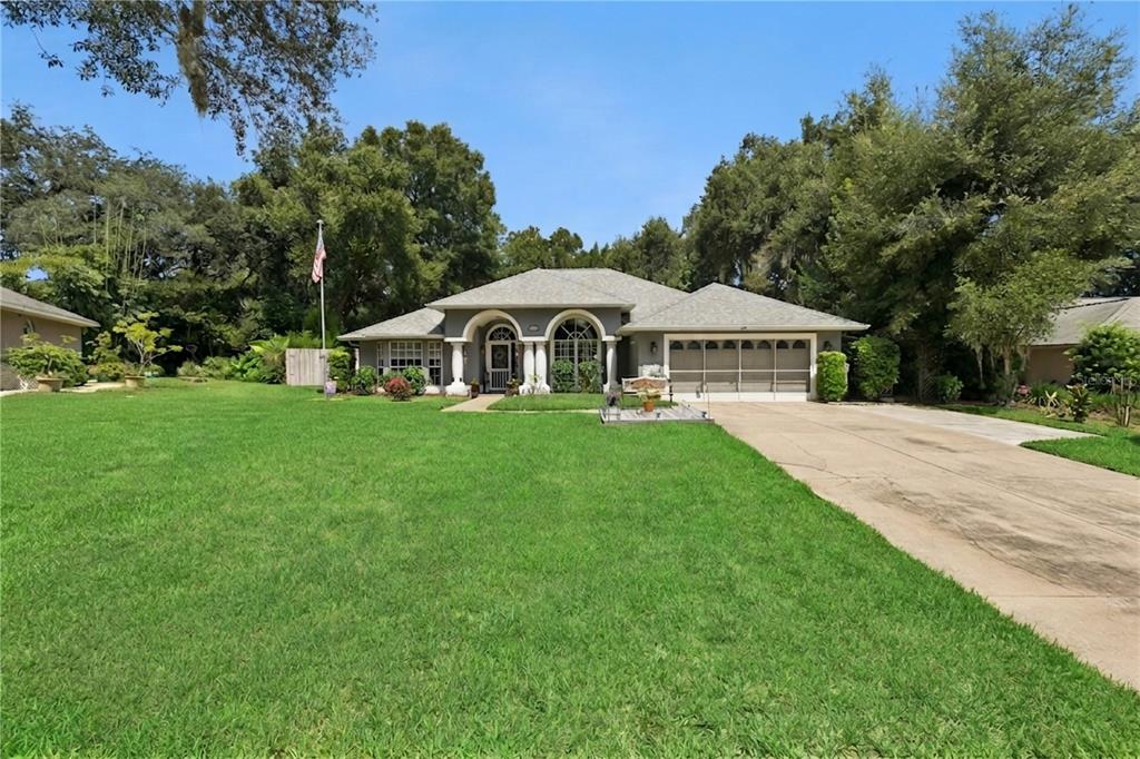 A single-story house with a gray exterior, arched windows, and a large front lawn — 33440 LAKE BEND CIRCLE, LEESBURG, FL