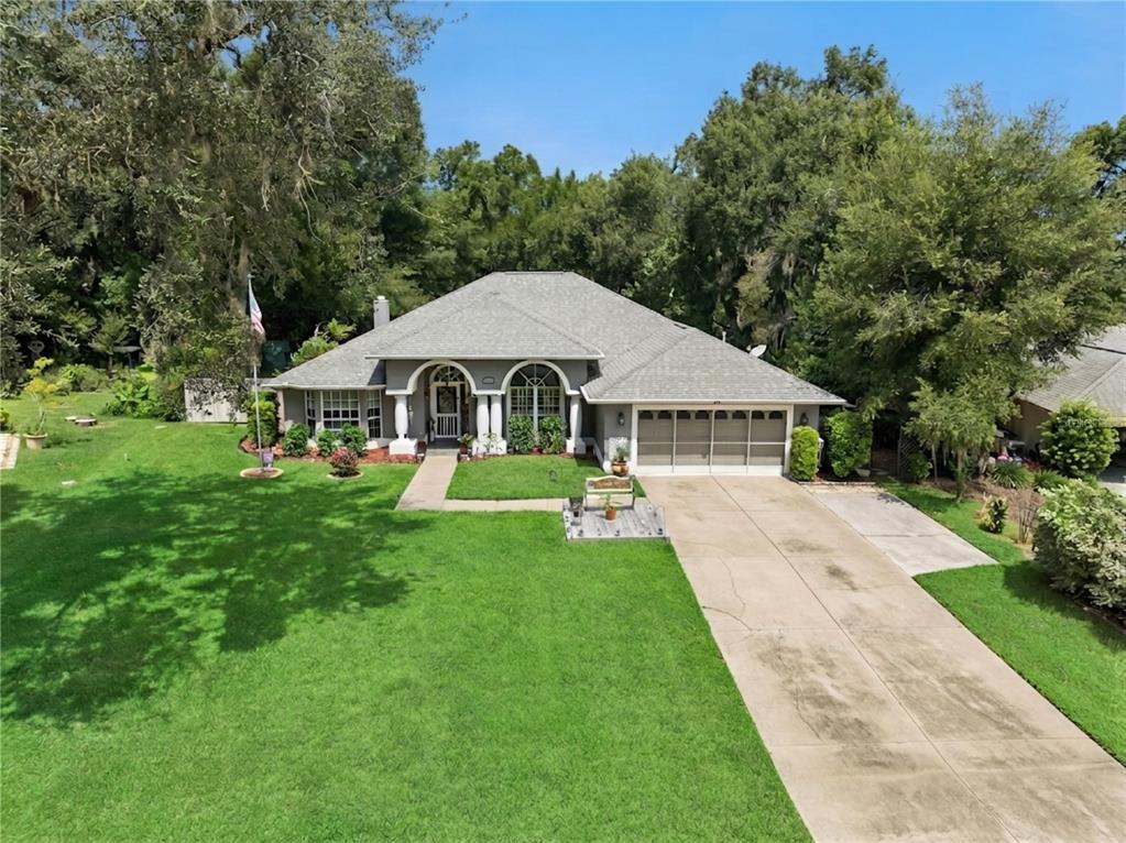 A single-story house with a gray roof, arched windows, and a large front lawn — 33440 LAKE BEND CIRCLE, LEESBURG, FL