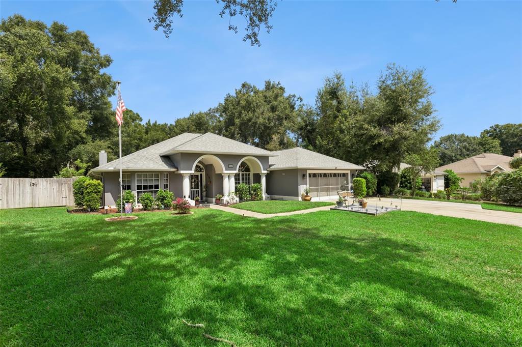 A single-story gray house with a two-car garage and a large front lawn — 33440 LAKE BEND CIRCLE, LEESBURG, FL
