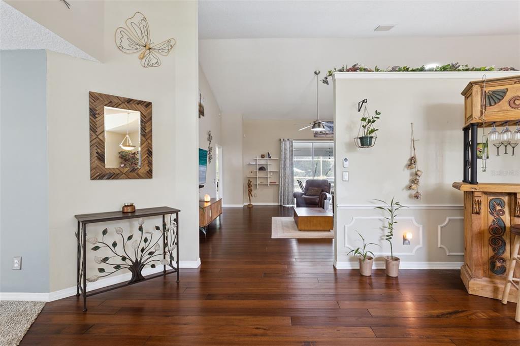 A view from a foyer into a living area with hardwood floors and a bar — 33440 LAKE BEND CIRCLE, LEESBURG, FL