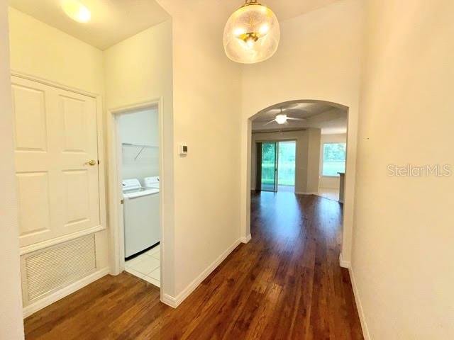 A hallway with wood-look flooring leads to an arched doorway and a laundry room — 4301 HEIRLOOM ROSE PLACE, OVIEDO, FL
