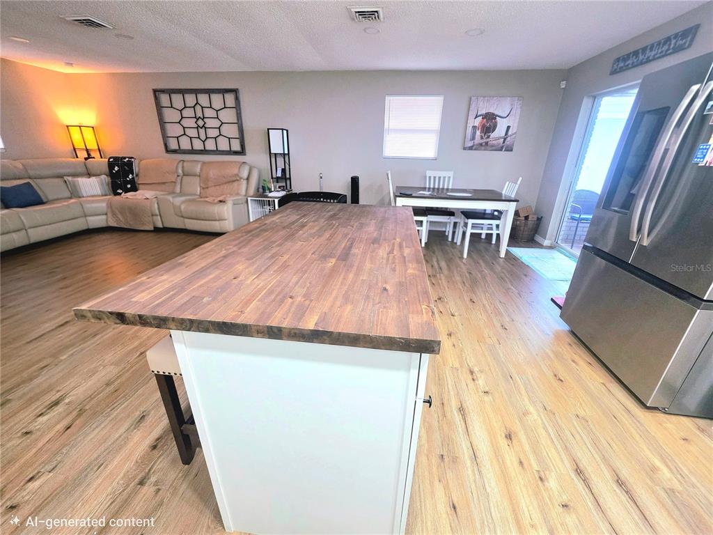 A kitchen island with a wood countertop sits in an open-concept living and dining area — 1380 EAGLE AVENUE E, EAGLE LAKE, FL