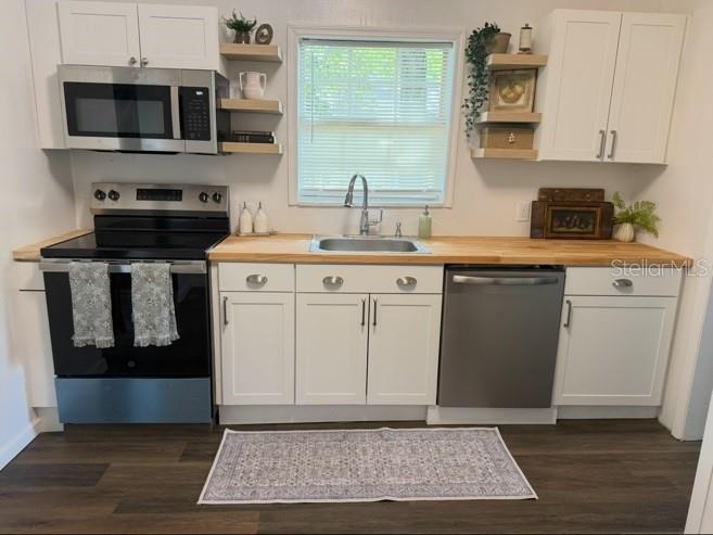 A kitchen features white cabinets, a stainless steel stove and dishwasher, and wood countertops — 1210 E 32ND AVENUE, TAMPA, FL