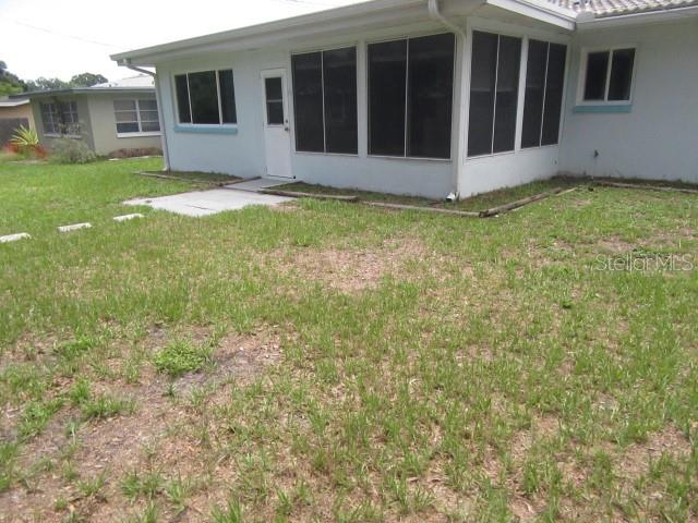 The exterior of a light blue house features a screened-in porch and a grassy yard — 890 7TH AVENUE NE, LARGO, FL