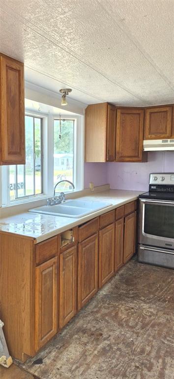 A kitchen features wood cabinets, a double-basin sink, and a stainless steel stove — 9285 SE 140TH PLACE, SUMMERFIELD, FL