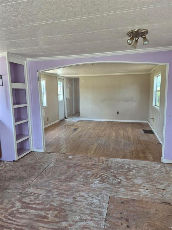 An interior view shows a room with exposed subflooring, purple walls, and a built-in bookshelf — 9285 SE 140TH PLACE, SUMMERFIELD, FL