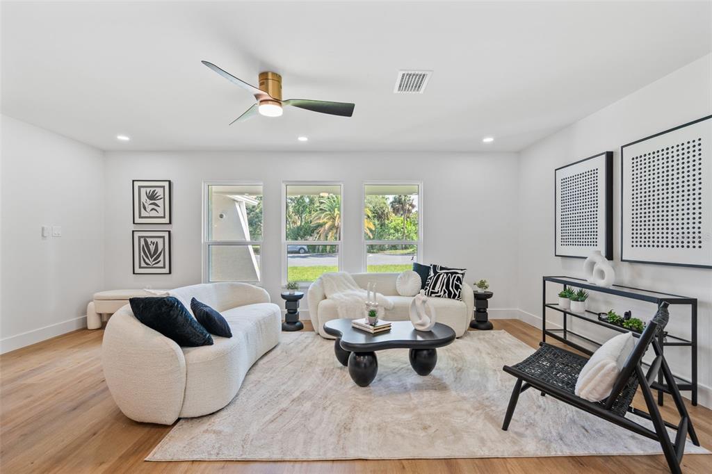 A bright living room features white curved sofas, a black coffee table, and wood flooring — 670 VENICE LANE, SARASOTA, FL