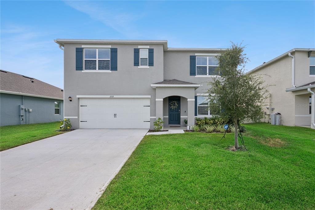 A two-story suburban house with a gray stucco exterior, blue shutters, and a concrete driveway — 3918 ROYAL AZALEA WAY, SANFORD, FL