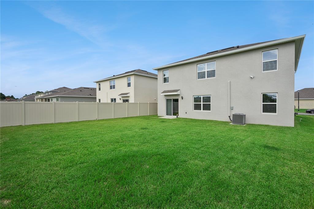 The backyard features a green lawn, a beige vinyl fence, and the rear exterior of a house — 3918 ROYAL AZALEA WAY, SANFORD, FL