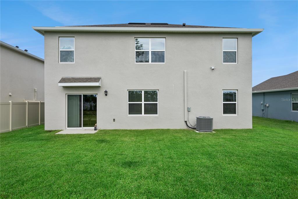 The rear exterior of a two-story house features a sliding glass door and lawn — 3918 ROYAL AZALEA WAY, SANFORD, FL