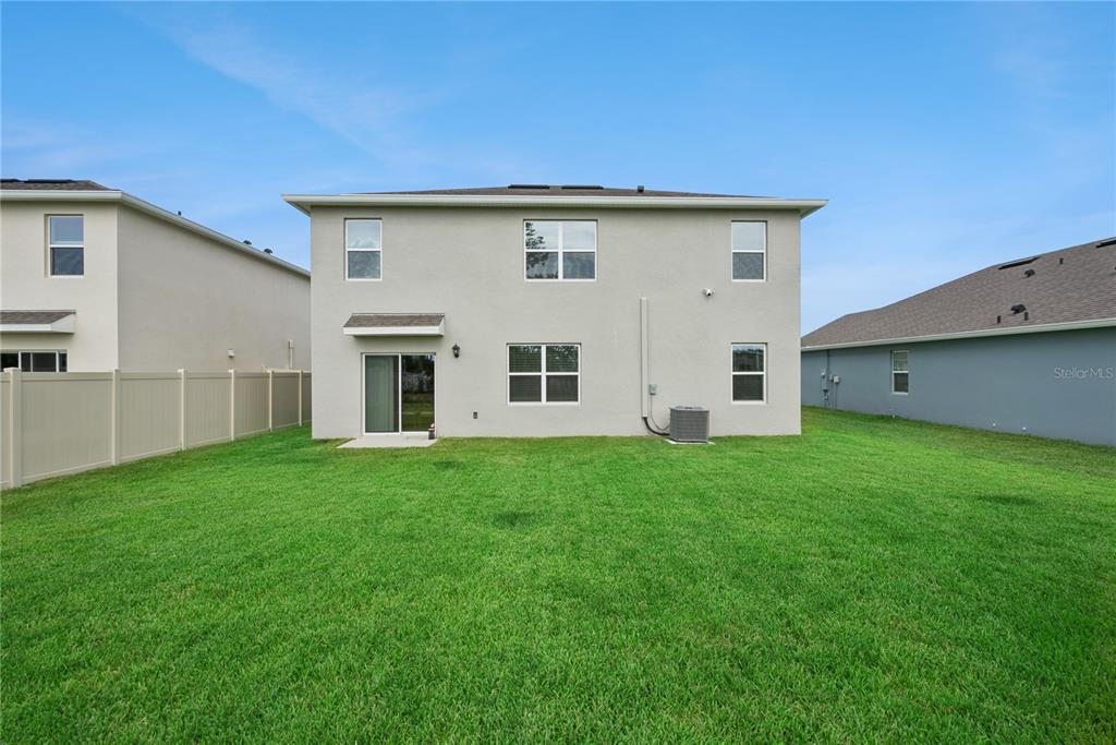 The rear exterior of a two-story house features a sliding glass door and a lawn — 3918 ROYAL AZALEA WAY, SANFORD, FL