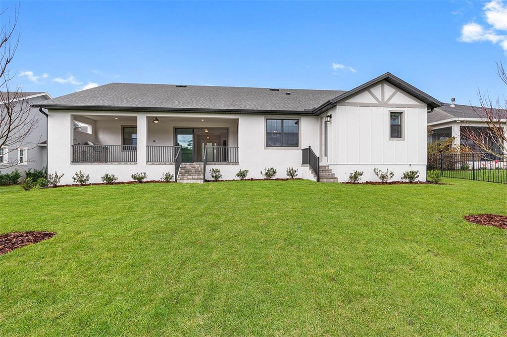 The rear exterior of a white house features a covered patio and a grassy lawn — 5601 SUMMIT VIEW DRIVE, BROOKSVILLE, FL