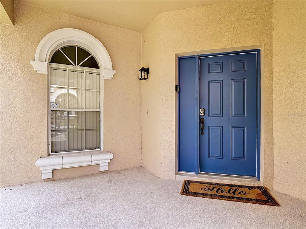 A front porch features a blue door, a window with an arched top, and a doormat — 672 ORISTA DR, DAVENPORT, FL