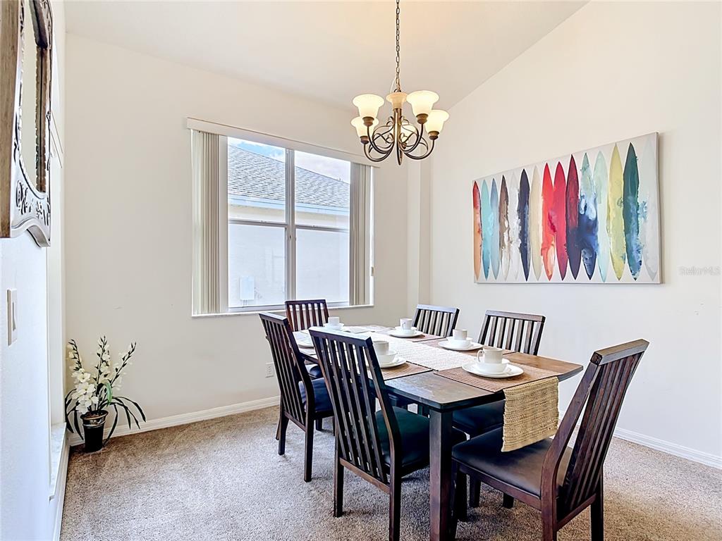 A dining room features a wooden table with six chairs, a chandelier, and wall art — 672 ORISTA DR, DAVENPORT, FL