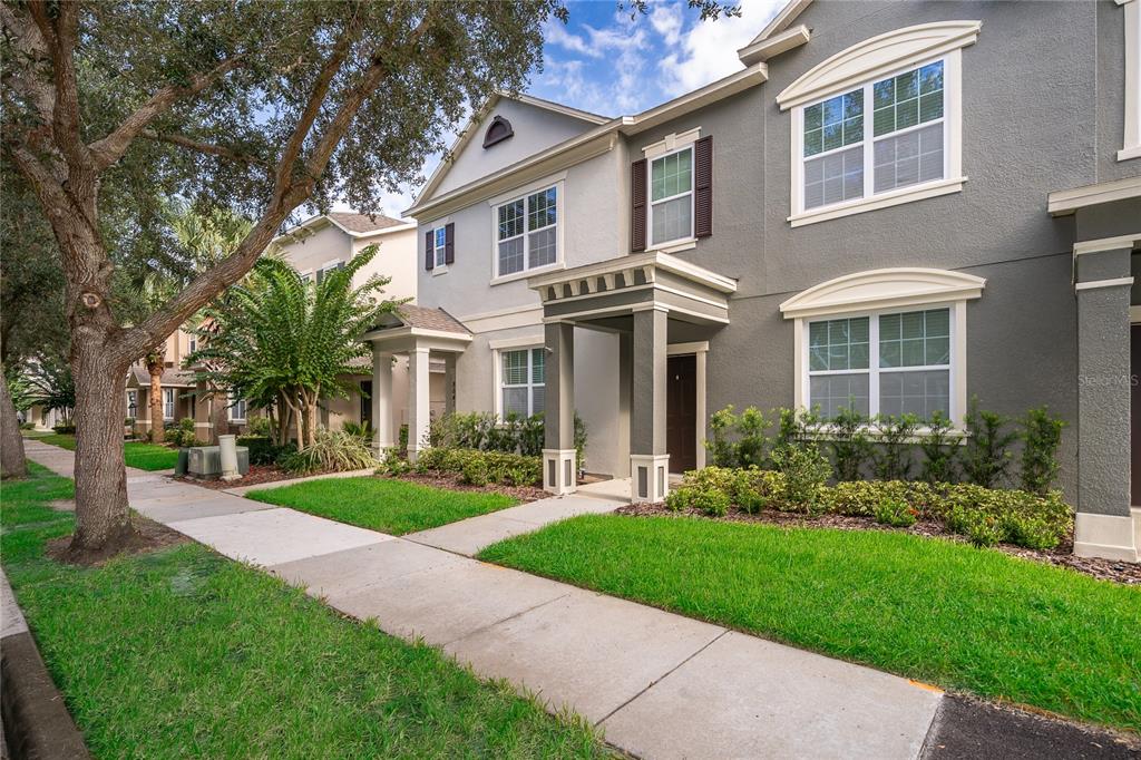 A two-story townhouse with a gray exterior, covered entryway, and a front lawn — 8641 BROOKVALE DRIVE, WINDERMERE, FL