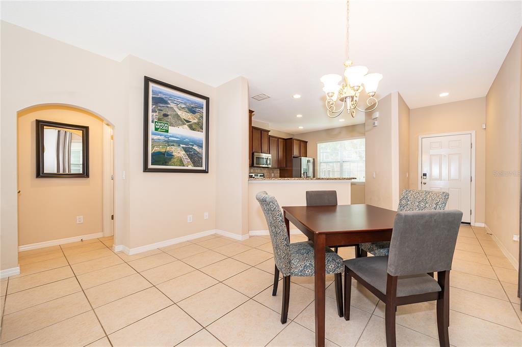 A dining area with tile floors, a wooden table, and an adjacent open kitchen — 8641 BROOKVALE DRIVE, WINDERMERE, FL