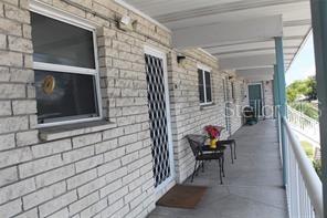 An outdoor walkway with brick walls, windows, and metal security doors leads to a balcony — 5357 81ST STREET N UNIT 24, ST PETERSBURG, FL