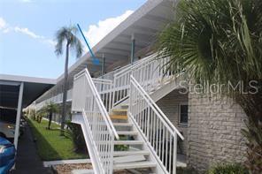 An exterior view of a two-story apartment building with white stairs and a covered walkway — 5357 81ST STREET N UNIT 24, ST PETERSBURG, FL