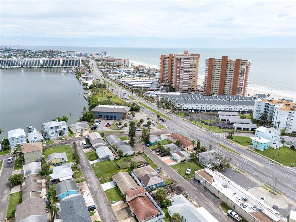 An aerial view shows a coastal neighborhood with houses, parking lots, and high-rise buildings — 18005 1ST STREET E, ST PETERSBURG, FL