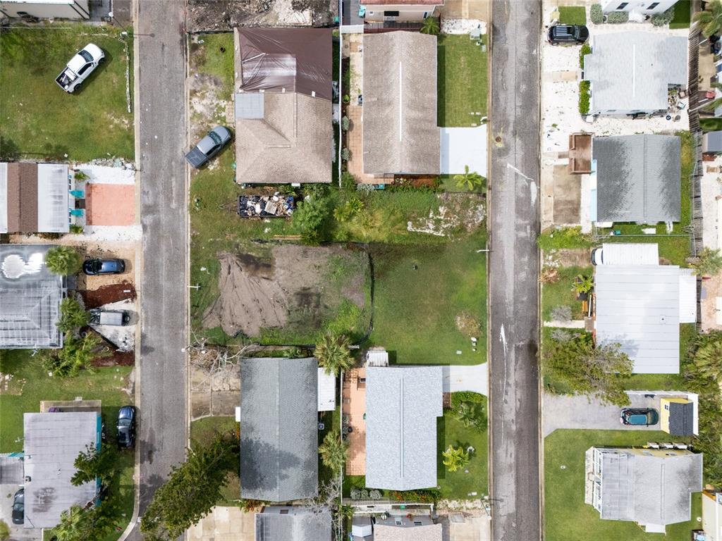 An aerial view shows a coastal neighborhood with houses, a road, and high-rise buildings — 18005 1ST STREET E, ST PETERSBURG, FL