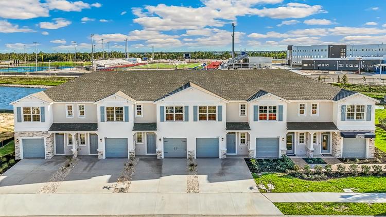 An exterior view of a multi-unit townhouse complex with gray garage doors and blue shutters — 10686 TIGER LILY DRIVE, VENICE, FL