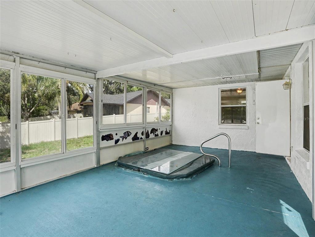 A sunroom with a blue floor features a built-in hot tub and large windows — 808 CHAMBERLAIN LOOP, LAKE WALES, FL